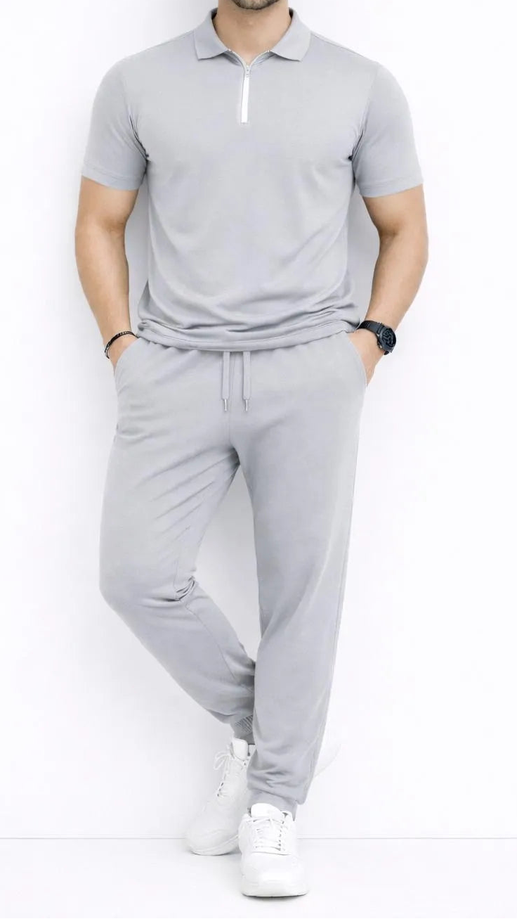 Man wearing a gray tracksuit with white sneakers on a white background