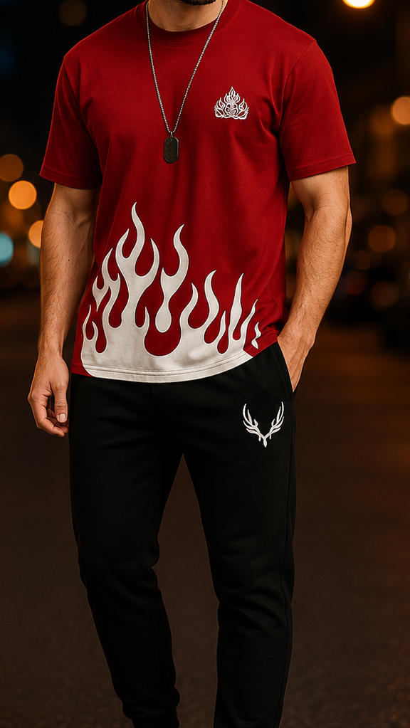 A man standing on a city street at night wearing a red t-shirt with a white flame graphic and a small white crest logo, paired with black jogger pants and white sneakers.